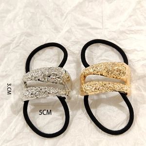 Detail of gold and silver hollow metal hair ties with hammered lava texture design