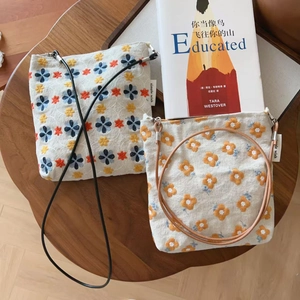 Détail de sacs bandoulière en toile vintage avec broderies florales et lanières en cuir