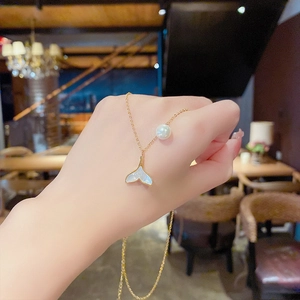 Golden mermaid tail necklace with white shell inlay and pearl detail on a long chain