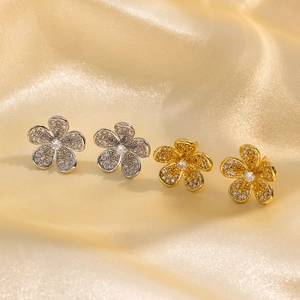 Elegant gold and silver flower stud earrings with zircons on silk background