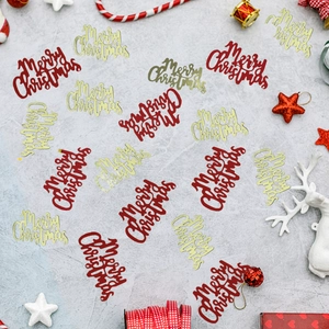 Macro shot of red and gold Merry Christmas confetti sequins for holiday table decoration
