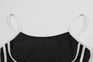 Detail of black camisole dress showing thin straps and white side stripes decor