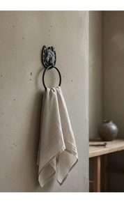 Detail of horse head horseshoe towel ring in cast iron with a beige towel on grey wall