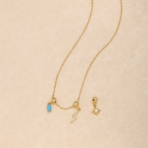 Detail of silver lightning bolt and blue teardrop pendant charms on gold necklace