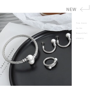 Detail shot of a steel cable jewelry set with pearls on a black tray display