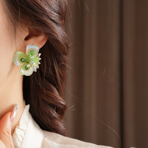 Gros plan d'une boucle d'oreille fleur avec pétales verts et perles sur un mannequin