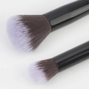 Gros plan détaillé de pinceaux de maquillage à double embout avec poils synthétiques bicolores
