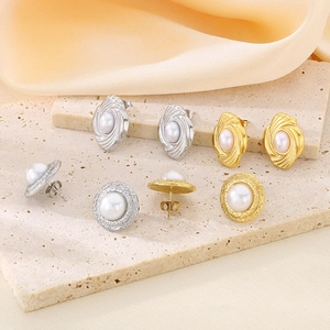 Detail of vintage gold and silver pearl earrings on a premium stone and silk surface