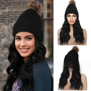 Detail of a black knitted beanie wig with long wavy hair and a brown faux fur pompom