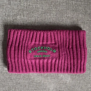 Details des lila Strick-Stirnbands mit grünem geprägtem Stockholm Sweden-Schriftzug