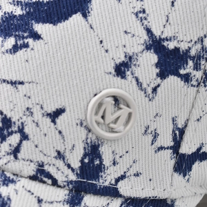 Detailansicht des Twill-Stoffs mit blauem Batikmuster und rundem M-Logo-Abzeichen