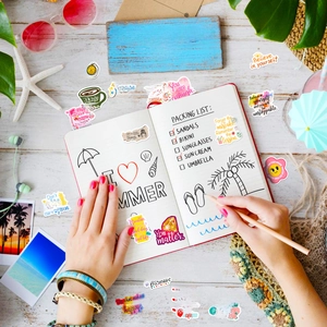 Flat lay of colorful inspirational quote stickers on a wooden desk with travel props