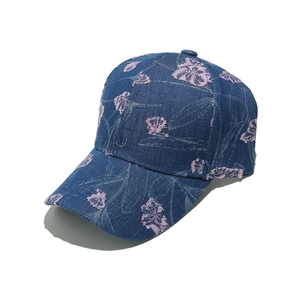 Close-up of blue denim baseball cap with pink floral embroidery and vintage distressed finish