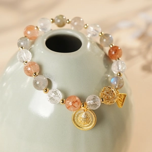 Macro detail of natural moonstone and crystal bracelet with golden Buddha charms