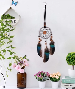 Detailed handmade dream catcher with brown feathers and wood beads on a white wall