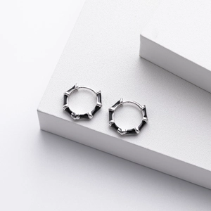 Detail of s925 silver bamboo hoop earrings with black enamel on a white podium