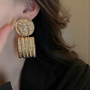 Macro shot of vintage gold embossed portrait earrings with geometric metal texture