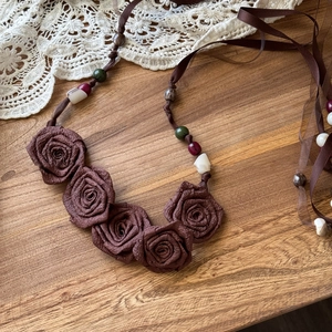 Vintage brown chiffon flower waist chain with wooden beads and ribbons on a rustic wood surface