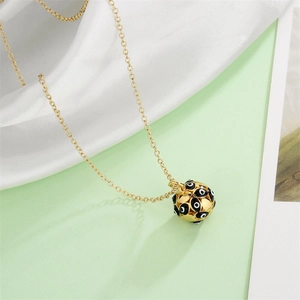 Detail of gold chain necklace featuring a white and black evil eye sphere pendant on silk