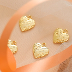 Golden heart-shaped metal charms with Made With Love engraving on ribbon background