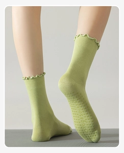 Detailed view of green mid-calf yoga socks with ruffle edges and anti-slip silicone grip