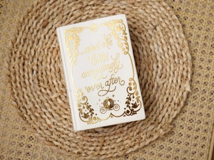 Top view of book-shaped white ceramic vase with golden inspirational text on a woven mat