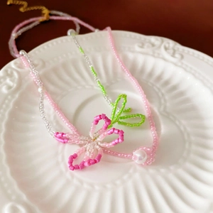 Detail of handmade beaded flower necklace set with pink beads and faux pearls in a ceramic tray