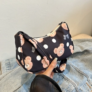 Cute black shoulder bag with cartoon bear and white polka dots in a hand-held view