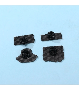 Détail du revers des badges en métal noir avec attaches en caoutchouc et texture maillée