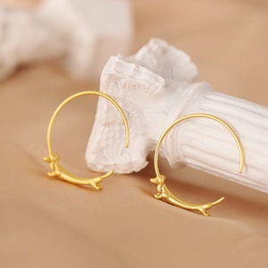 Detailed view of matte gold dachshund dog pendant earrings on creative ring hooks