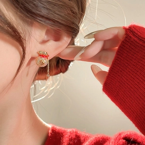 Gros plan de boucles d'oreilles porte-bonheur dorées et rouges avec pompons sur un mannequin