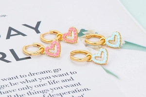 Detail of pink and blue enamel heart hoop earrings with elegant golden metal finish