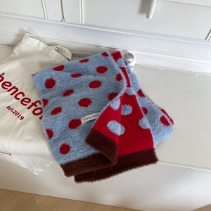 Detail of plush scarf featuring red and blue polka dots with a small brand label