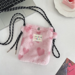 Close-up of pink plush shoulder bag with heart patterns and sozakka logo label