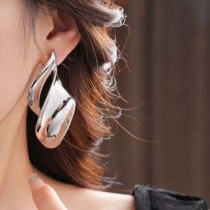 Close-up of a high-polished silver irregular twisted leaf earring on a model