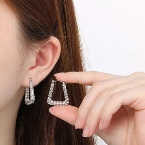 Close-up of silver U-shaped hoop earrings with diamond inlay worn by a model
