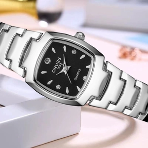 Close-up of a silver square watch with a black dial and rhinestone markers on a white stand