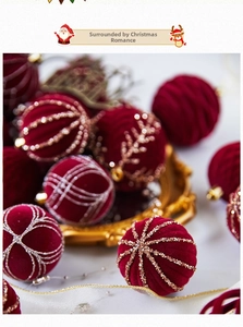 Detail of burgundy flocked Christmas ball with gold glitter patterns and hanging loop