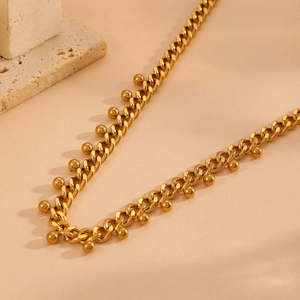 Detail view of a gold Cuban chain necklace with multiple metallic ball pendants