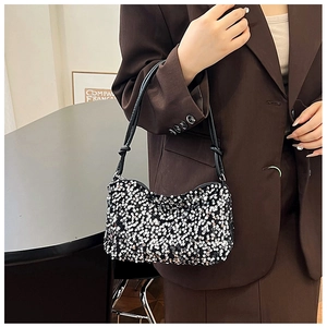 Close-up of black sequined baguette bag with silver discs and knotted leather strap
