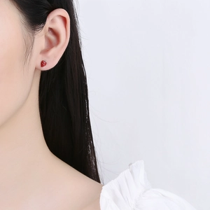 Cute red strawberry stud earrings worn by a model showcasing realistic fruit texture