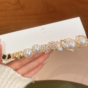 Detailed macro view of vintage gold hair clip with pearls and black geometric accents