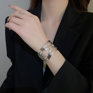 Macro shot of silver hollow geometric bracelet and matching ring on a model