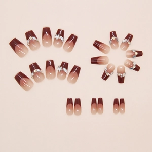 Macro detail of wine red French ombre press-on nails with rhinestones and pearl accents