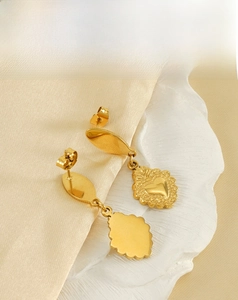 Close-up of vintage gold heart earrings with embossed patterns on silk and ceramic tray