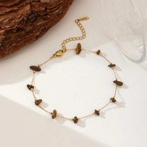 Macro detail of stainless steel gold chain with irregular brown natural stone beads