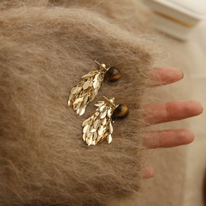 Detailed macro of golden leaf tassels and brown marble beads on vintage earrings