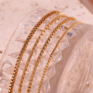 Macro shot of 18K gold plated stainless steel box chains on textured glass surface