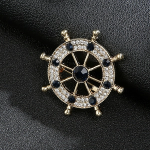 Macro shot of gold ship wheel brooch with blue gemstones and diamonds on black leather