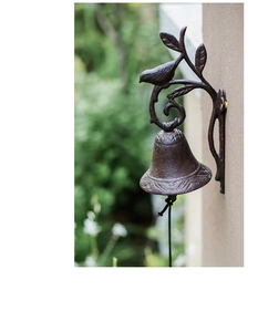 Detailed view of vintage cast iron door bell with bird and leaf design on beige wall